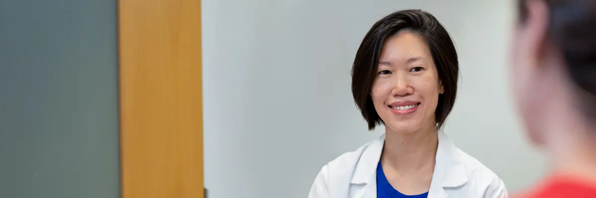 Gastrointestinal medical oncologist Dr. Jessica Yang, wearing a doctors’ white coat, smiles as she talks with her patient.