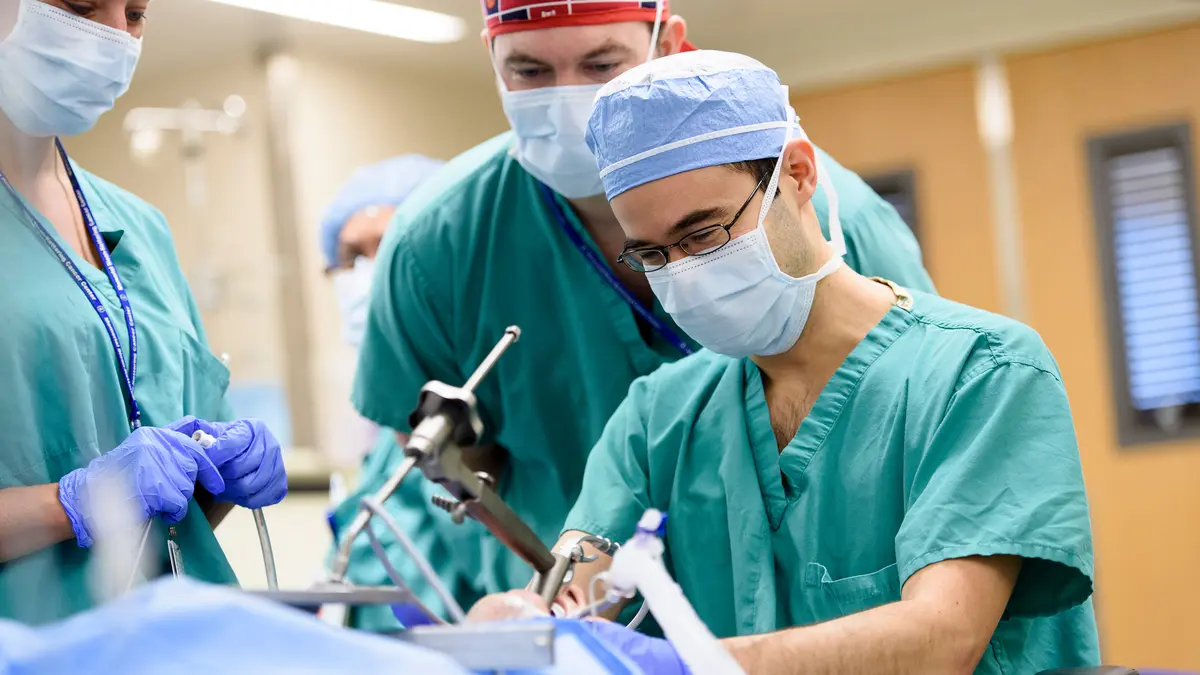 Head and neck surgeon Dr. Luc G. T. Morris uses an instrument on the patient while 2 MSK colleagues help with the surgery. 