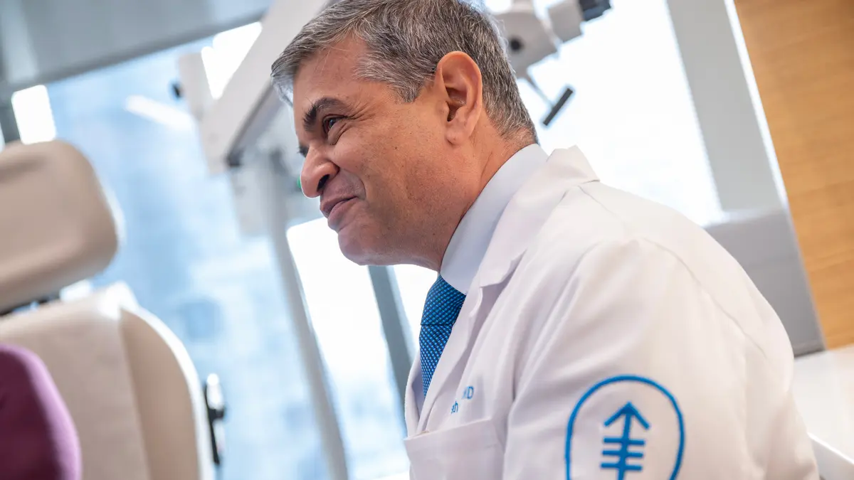 A surgeon wearing a white doctors’ coat is in an MSK exam room. 