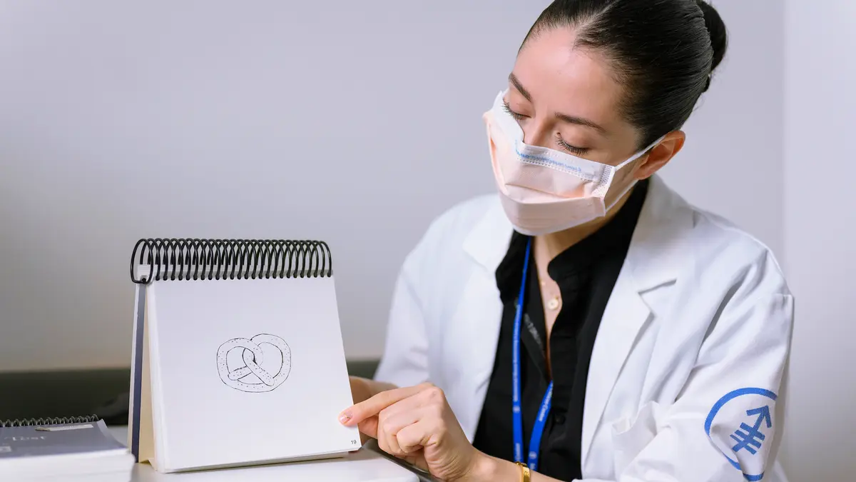 An MSK speech pathologist points to a sketch pad with a drawing of a pretzel. 